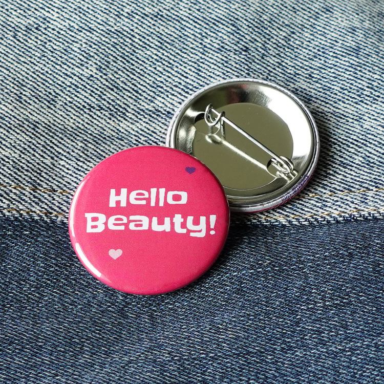 Ansteckbutton Hello Beauty! auf Jeans mit Rückseite